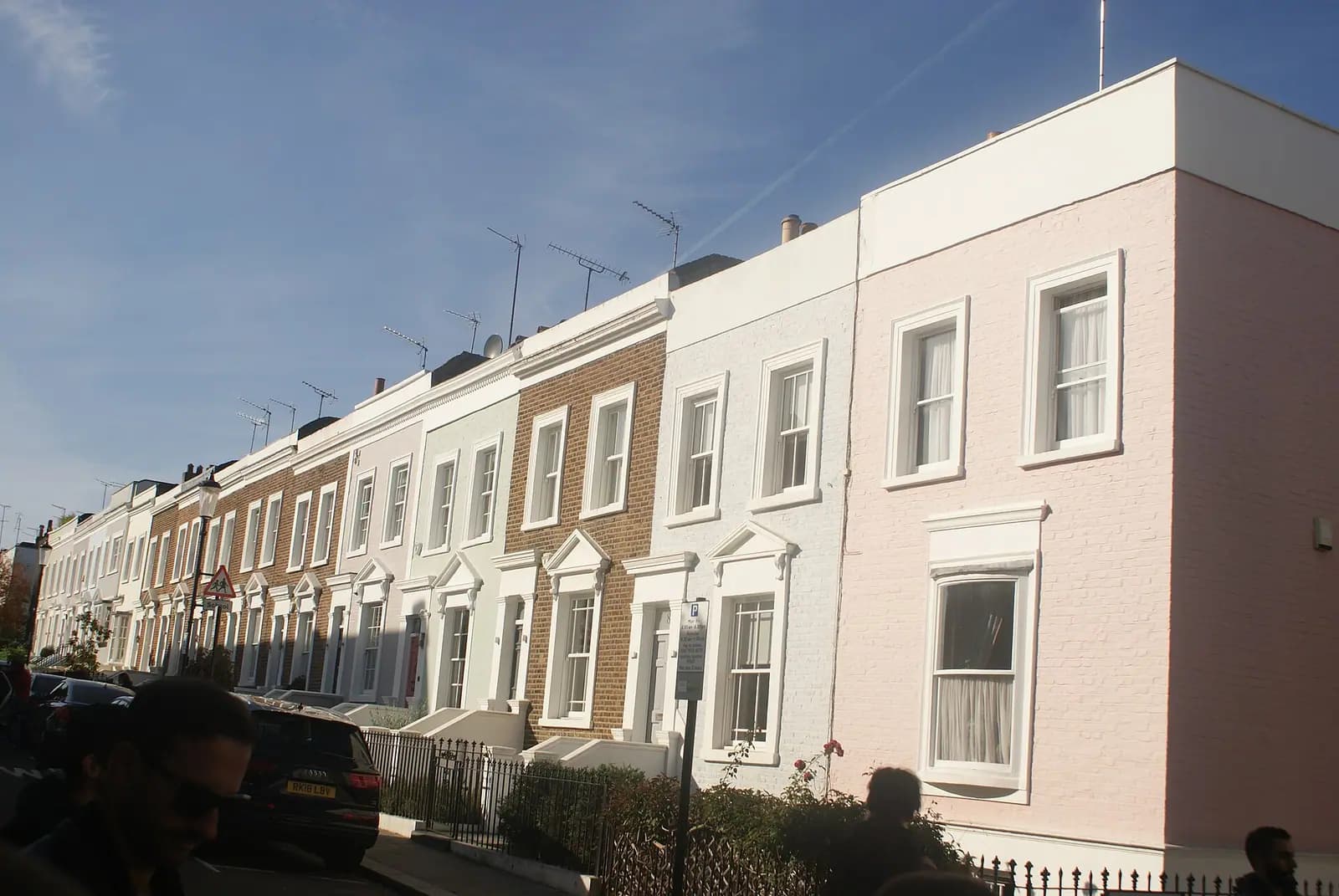 A terrace of low painted houses in pink, white and brown on Kensington Place, with white window surrounds and small basement areas behind railings