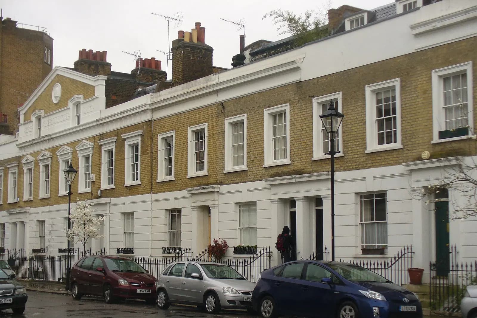 A terrace of yellow-brick Georgian houses with white stucco ground floors and sash windows on Gladstone Street in Southwark, with a gas-style street lamp