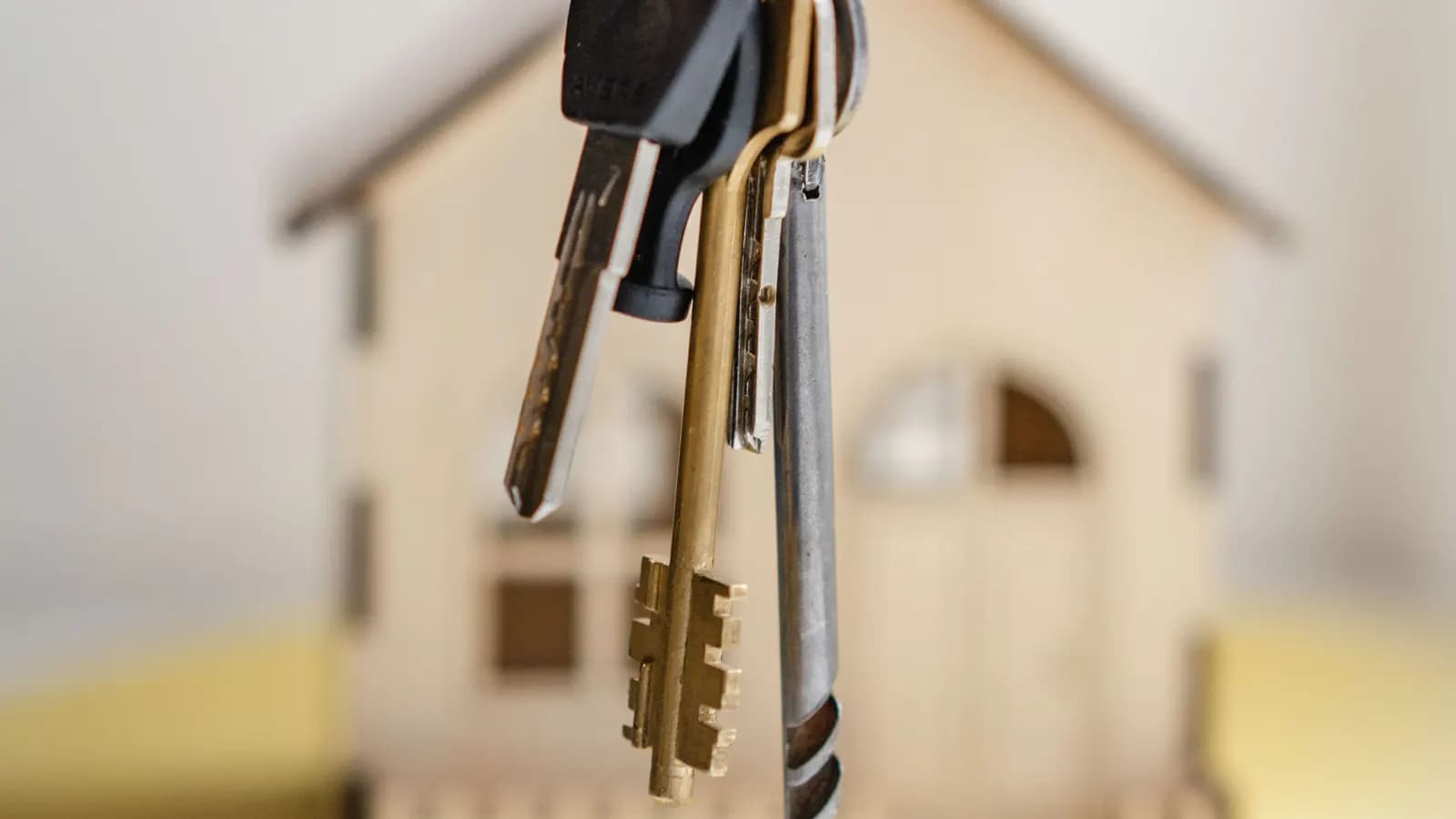 A bunch of keys hanging in front of a blurred small wooden house model